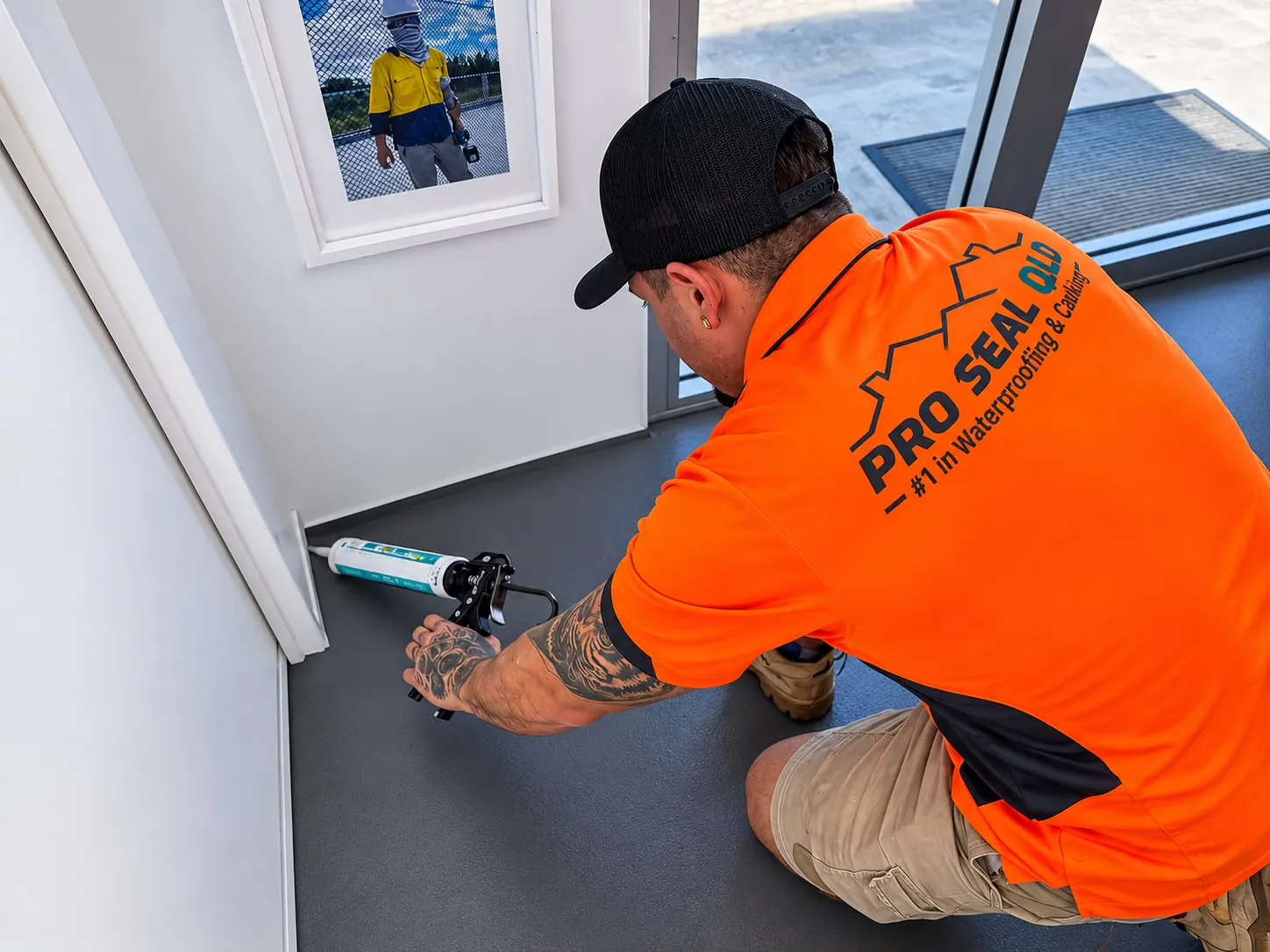 A Pro Seal QLD technician in an orange shirt running a bead of sealant along a skirting board